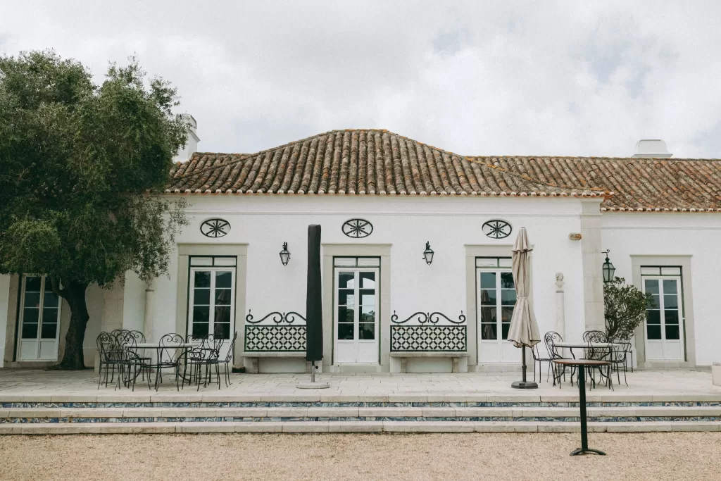 Outdoor terrace at Herdade do Peru with wrought iron furniture and whitewashed walls beneath a tiled roof.