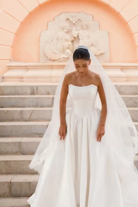 Bride looks down gracefully on the steps in front of the peach archway at Hospes Maricel & Spa.