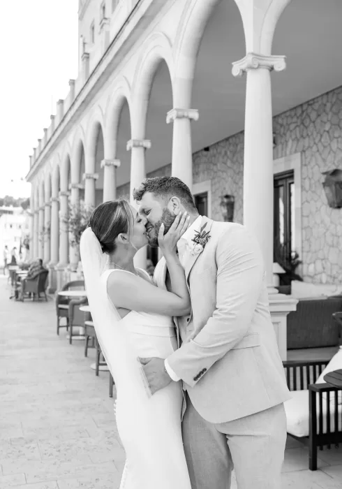 Bride and groom share a romantic kiss under the stone arches of Hospes Maricel & Spa.