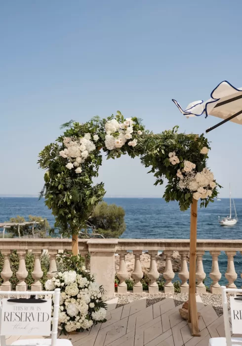 Close-up of lush green and white floral arch at Hospes Maricel & Spa with sea views in the background.