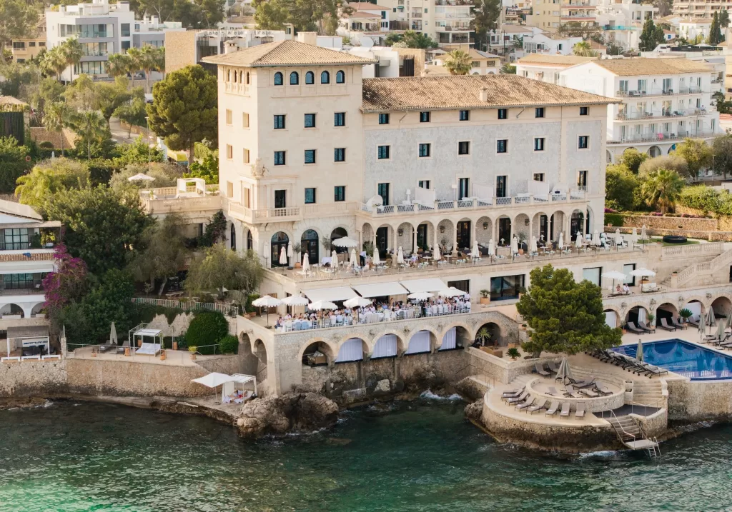 Aerial view of Hospes Maricel & Spa, a historic cliffside hotel overlooking the Mediterranean Sea.
