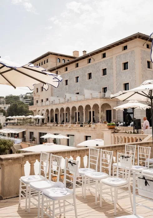 Sunlit terrace ceremony space at Hospes Maricel & Spa with elegant white chairs and Mediterranean views.