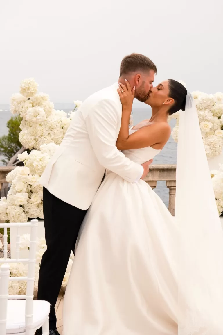 Bride and groom share a romantic first kiss surrounded by white flowers at Hospes Maricel & Spa.