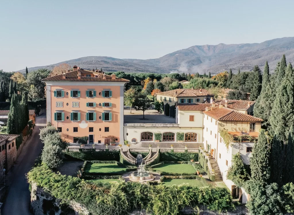 Aerial view of Il Borro estate showing its grand villa, terraced gardens, and surrounding Tuscan countryside.