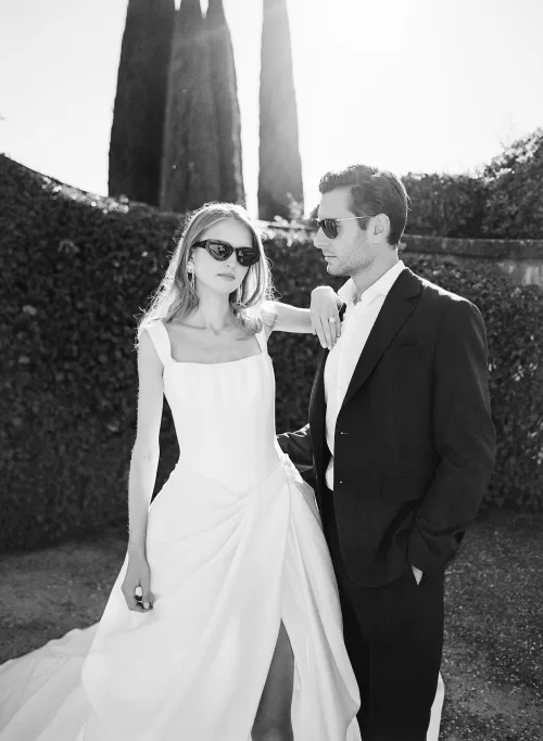 Bride and groom in chic wedding attire wearing sunglasses, captured in elegant black and white at Il Borro.