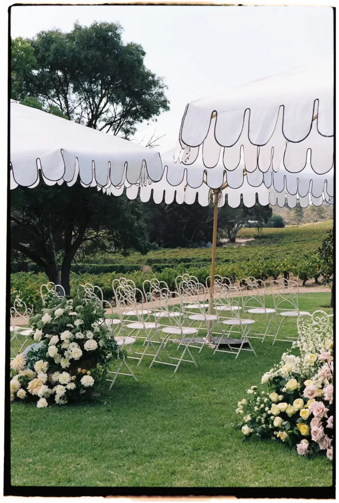Outdoor ceremony setup at Le Mas Barossa with floral arrangements and scalloped umbrellas.