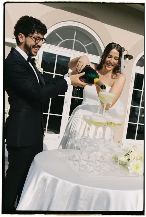 Bride and groom pouring champagne into a tower of coupe glasses outside Le Mas Barossa.