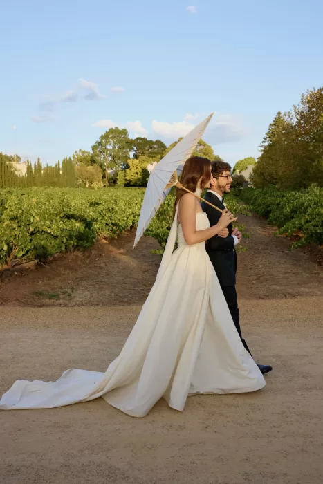 Bride and groom walking through the vineyards at sunset at Le Mas Barossa.