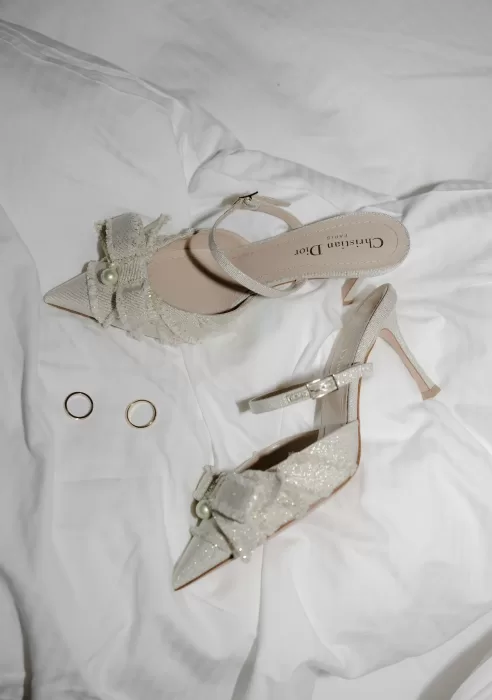 Bridal accessories at Manor House featuring Dior heels with pearl bows and the couple’s gold wedding rings.