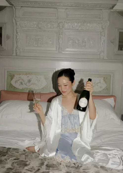 The bride enjoys a quiet morning at Manor House, smiling as she toasts with champagne in her silk robe.