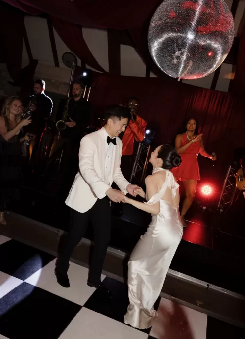 The couple dance beneath a glittering disco ball during their lively Manor House wedding reception.