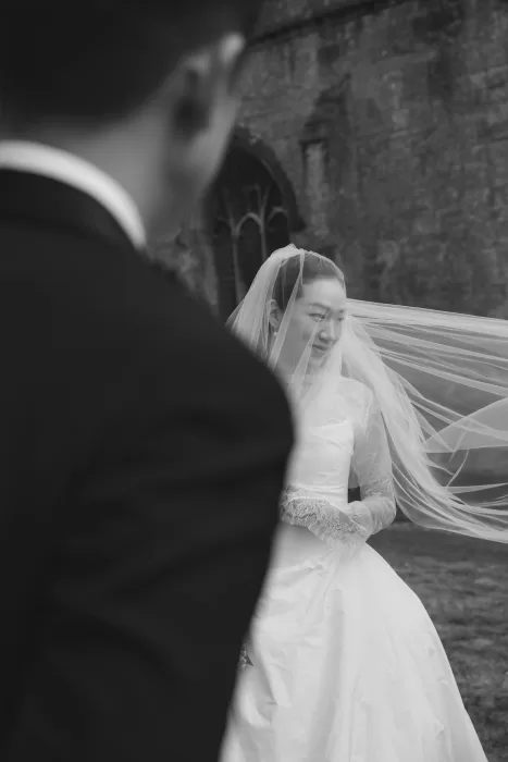 A candid moment as the bride’s veil catches the wind outside Manor House, her joyful smile framed by lace.