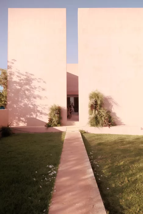 Sunlit pathway leading to the ceremony entrance framed by modern pink walls at Neuendorf House.