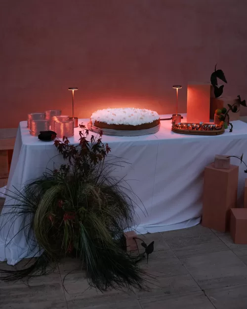 Minimalist dessert table lit by warm light against the terracotta walls of Neuendorf House.
