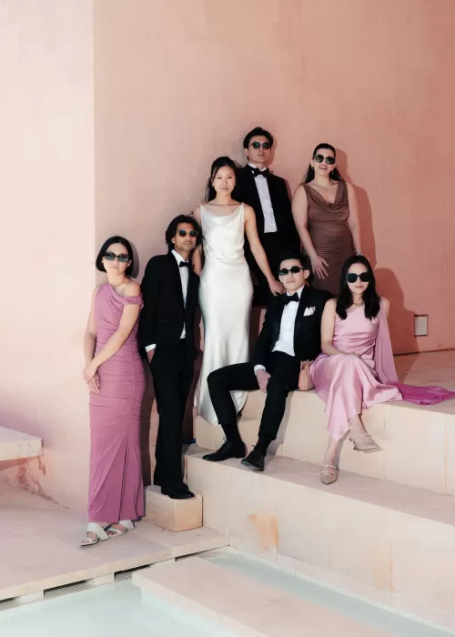 Wedding party posing in chic pastel attire against the pink minimalist walls of Neuendorf House.