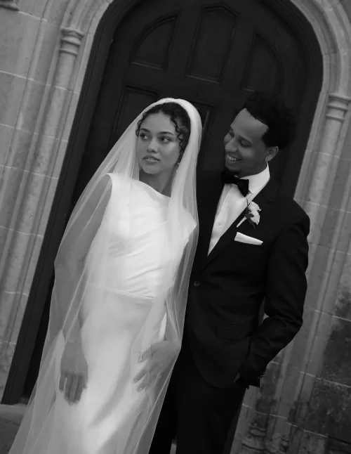 Elegant black and white portrait of the bride and groom standing outside The Plummer House entrance.