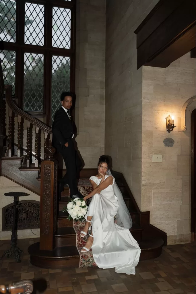 Bride and groom pose on the ornate staircase with rich wood paneling inside The Plummer House.