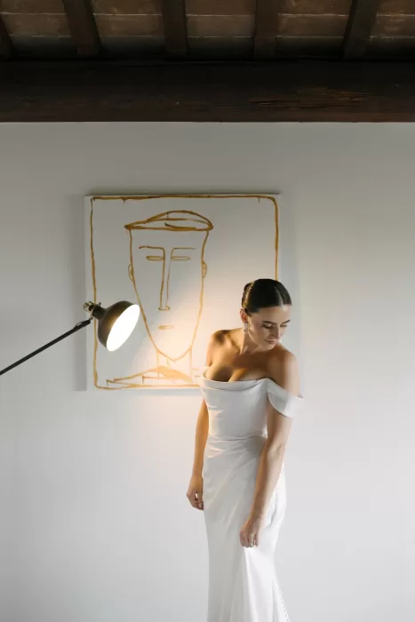 Bride adjusting her gown in a modern Tuscan room at Quercia al Poggio before the ceremony.