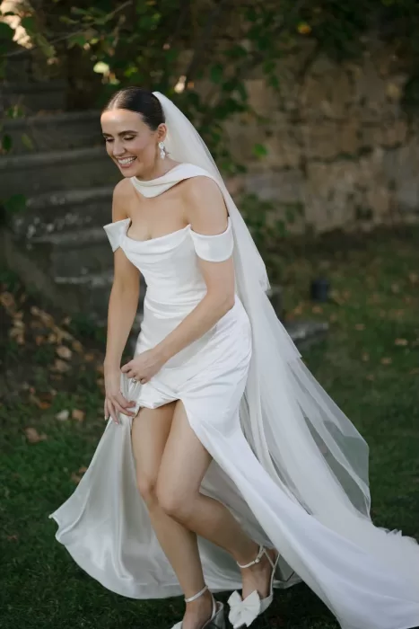 Bride smiling and lifting her gown in the garden at Quercia al Poggio, surrounded by greenery.