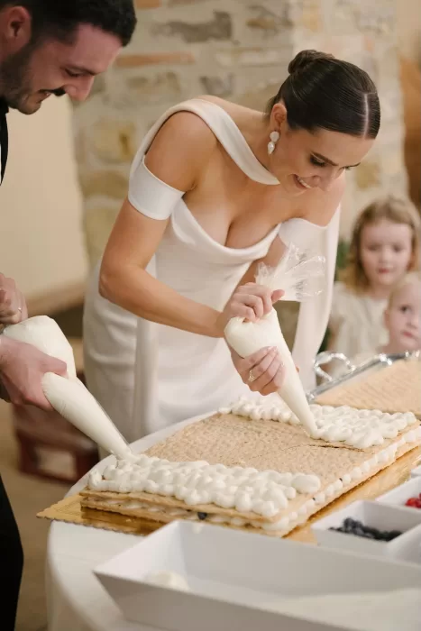 Bride joyfully decorating the wedding cake during the celebration at Quercia al Poggio.
