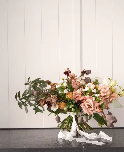 Textured bridal bouquet of peach, cream, and rust blooms with trailing ribbon at Quinta Dos Santos.