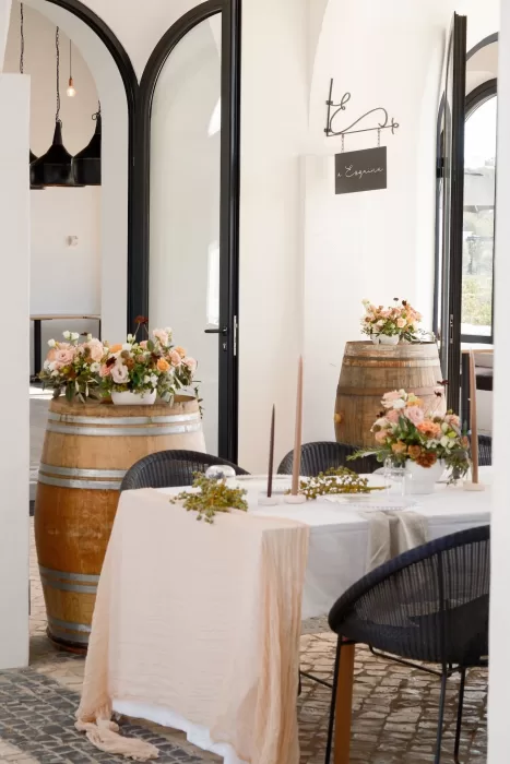 Romantic indoor wedding setup at Quinta Dos Santos featuring wine barrels, blush linens, and floral centerpieces.