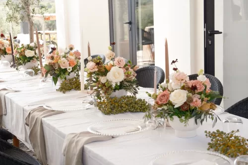 Elegant wedding table at Quinta Dos Santos adorned with soft peach and white floral arrangements and taper candles under natural light.