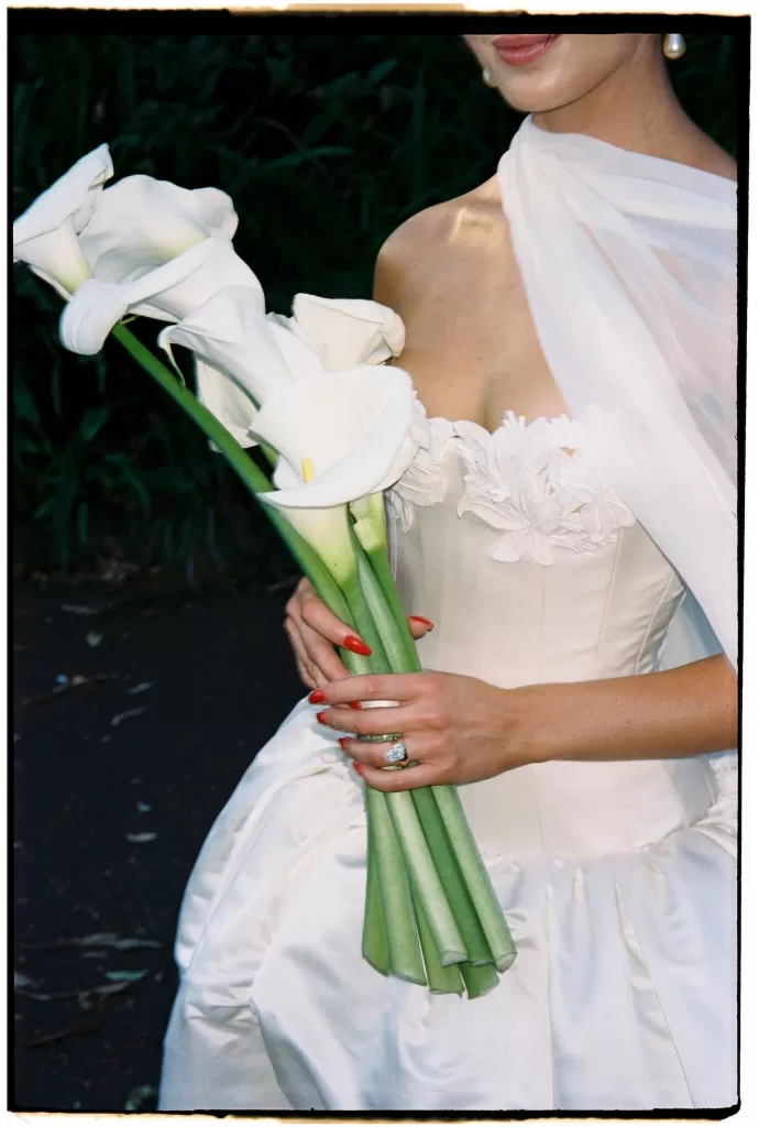 Close-up of bride holding white calla lily bouquet in satin gown at Sergeants Mess.