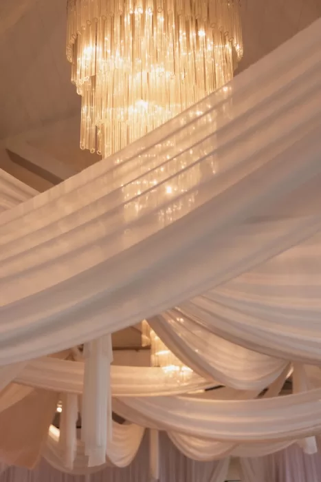 Sparkling chandelier and flowing white drapes decorating Sergeants Mess reception hall.