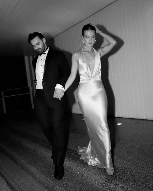 Black and white photo of couple holding hands walking down steps at Sergeants Mess.