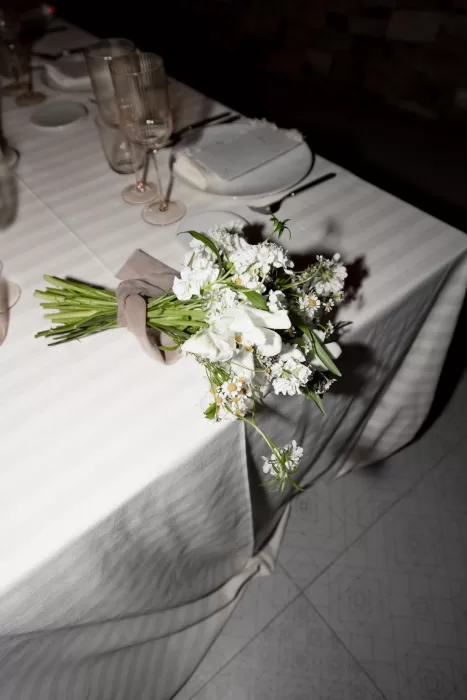 Bridal bouquet resting on the reception table at This Must Be The Place, surrounded by elegant glassware.