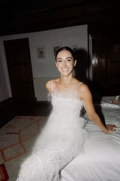 Bride in feathered evening gown smiling indoors at This Must Be The Place after the ceremony.