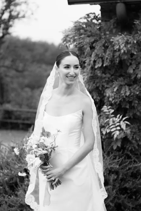 Black and white portrait of the bride holding her bouquet outside This Must Be The Place, smiling softly.