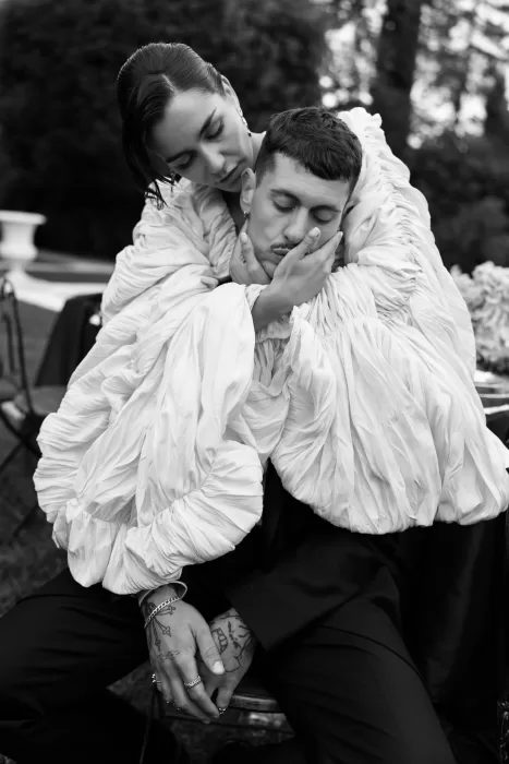 Black and white portrait of a bride tenderly embracing her groom in sculptural ruffled attire at Villa Balbiano.