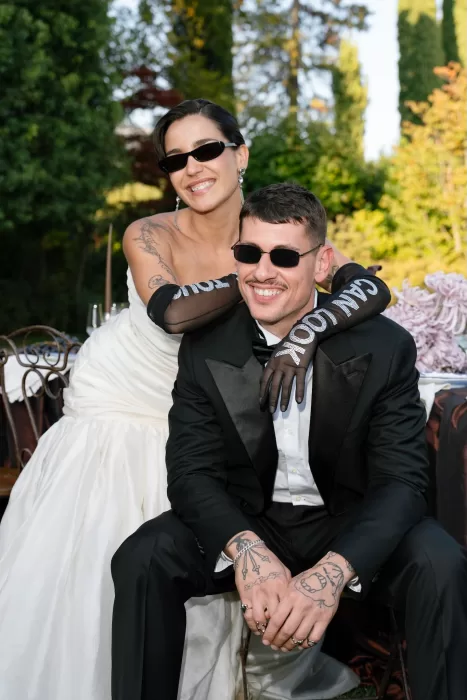 Bride and groom in chic black and white outfits smiling together in Villa Balbiano’s garden.