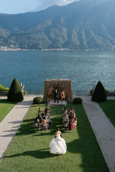 Wedding ceremony overlooking Lake Como with mountains and gold draped altar at Villa Balbiano.
