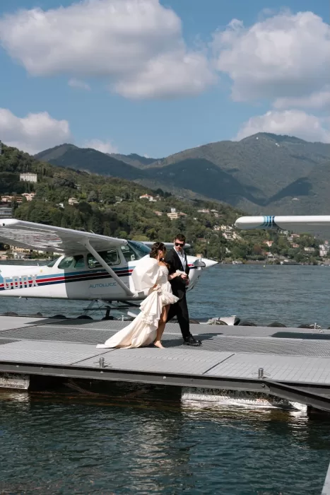 Bride and groom stepping off a seaplane onto Lake Como’s dock at Villa Balbiano.