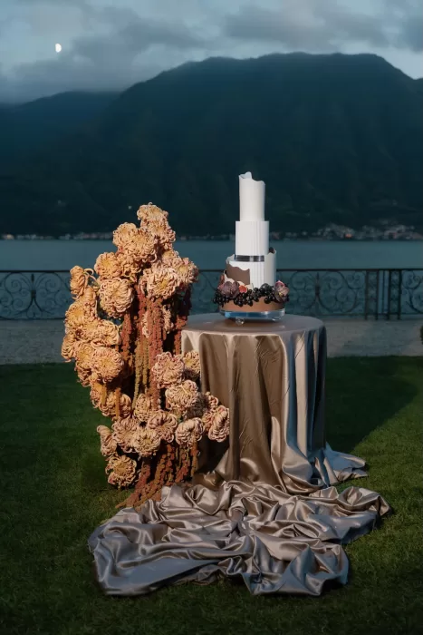 Modern wedding cake styled beside sculptural floral arrangements with Lake Como views at Villa Balbiano.
