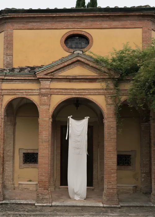 The historic chapel entrance at Villa Catignano with a draped white wedding banner hanging beneath the brick archways.