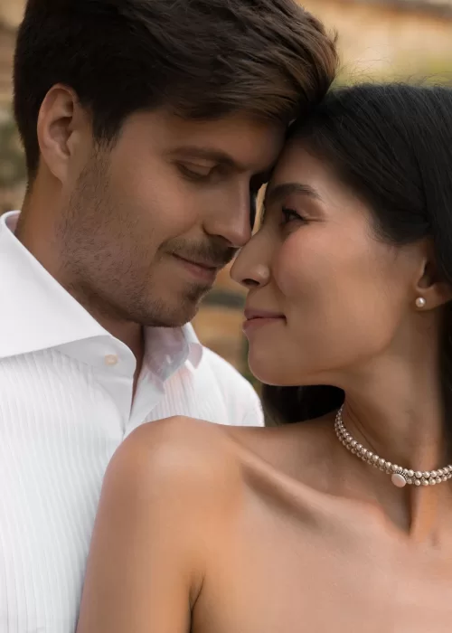Intimate close-up of the couple touching foreheads, the bride wearing a pearl choker at Villa Catignano.