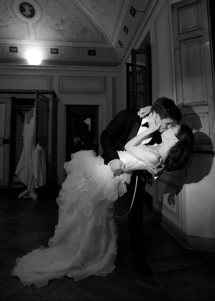 Romantic black and white photo of the couple sharing a kiss while dancing inside Villa Catignano.