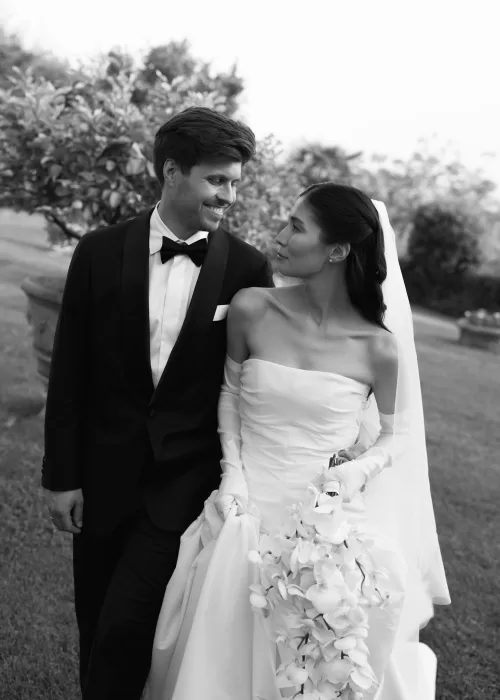 Black and white portrait of the bride and groom walking through Villa Catignano’s garden, smiling lovingly at each other.