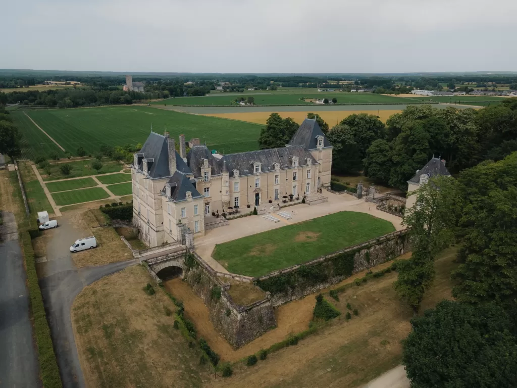 Aerial view of Château de Jalesnes surrounded by lush gardens and countryside fields in France.