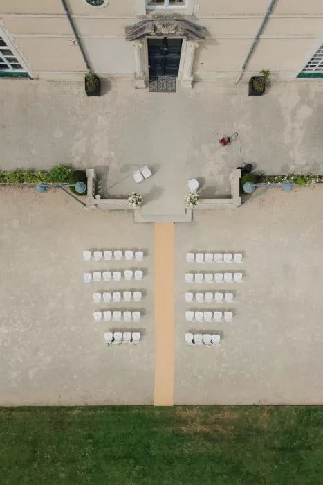 Outdoor wedding ceremony setup with white chairs facing the entrance of Château de Jalesnes.