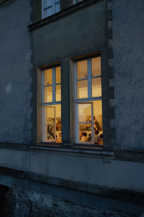 Warmly lit evening dinner scene viewed through the windows of Château de Jalesnes.