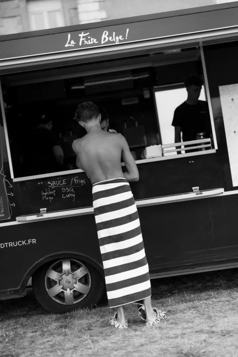 Guest ordering from a food truck at Château de Jalesnes, wrapped in a striped towel.