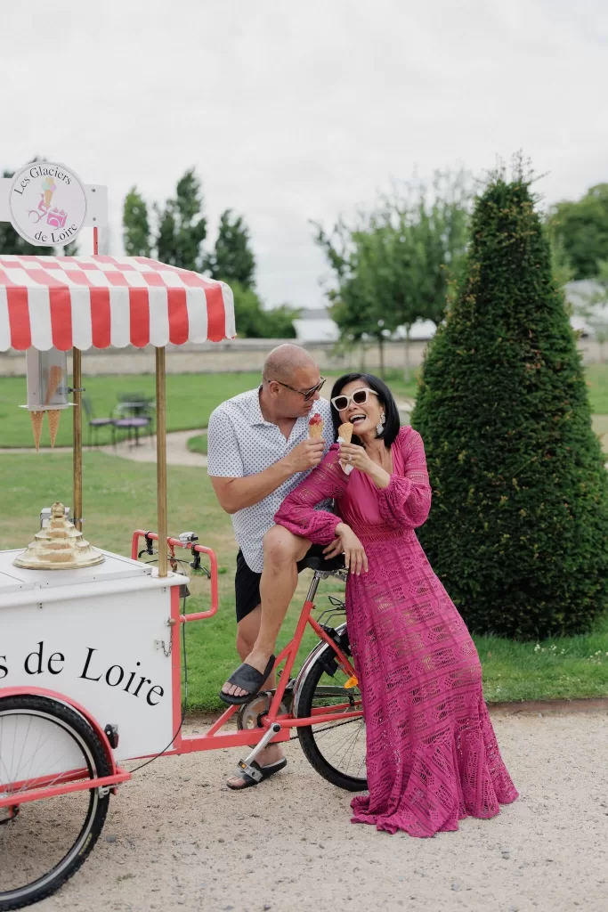 Couple enjoying ice cream by a vintage cart at Château de Jalesnes, capturing a playful pre-wedding moment.