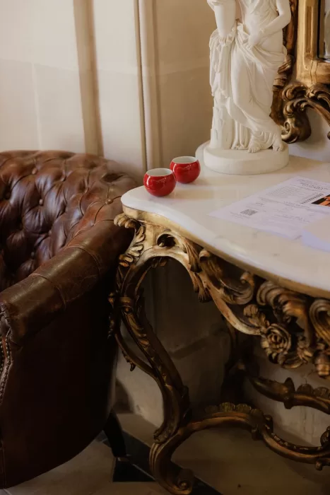 Vintage leather chair and ornate marble table with red tea cups inside Château de Jalesnes.