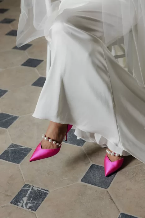 Bride wearing satin pink heels with pearl ankle straps beneath her wedding gown at Château de Jalesnes.