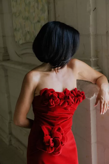 Elegant woman in a red floral gown posing inside Château de Jalesnes’ ornate interiors.